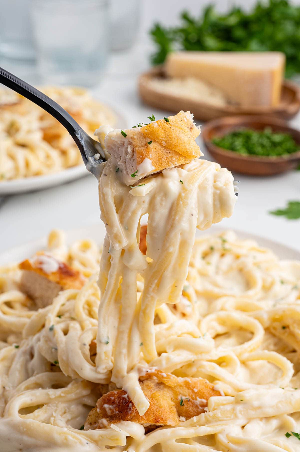 Fork twirls creamy chicken pasta with parsley garnish.