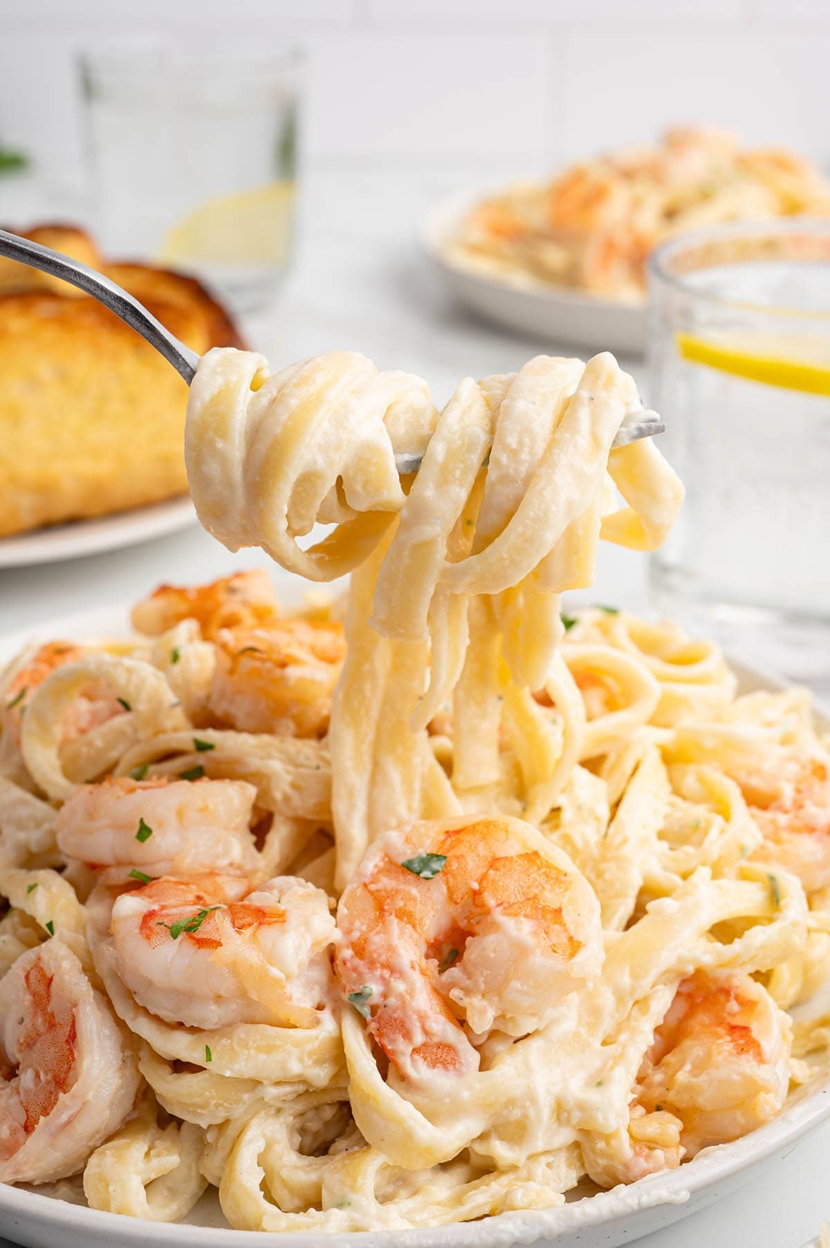 Creamy shrimp alfredo pasta in a black skillet, topped with parsley and shrimp.