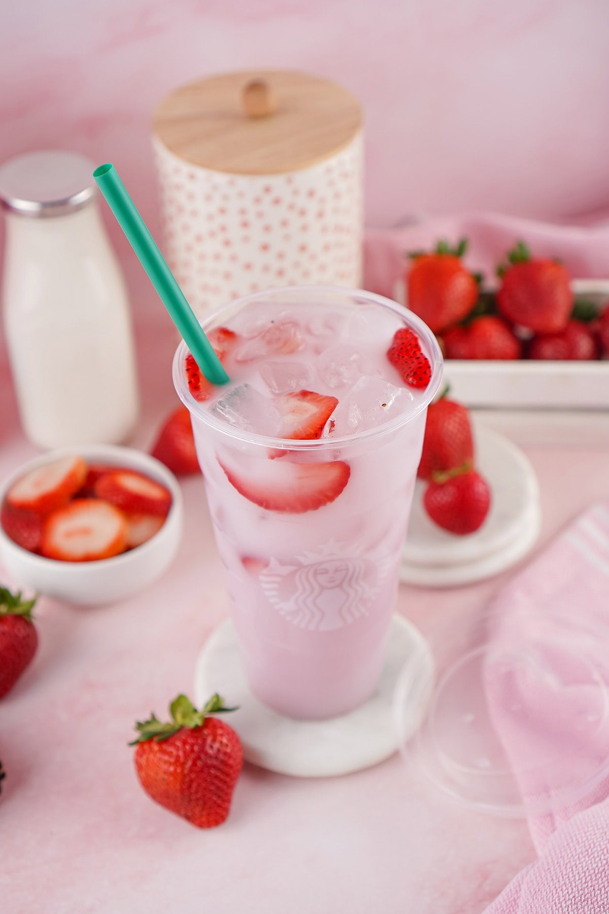 Starbucks Pink Drink with strawberry chunks and ice in a tall cup.