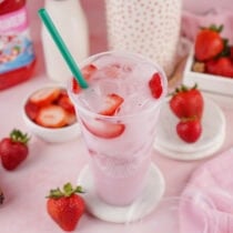 Copycat Starbucks Pink Drink with fresh strawberries and a green straw on a pink background.