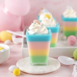 Layered pastel jello cups with whipped cream and Easter egg candies.