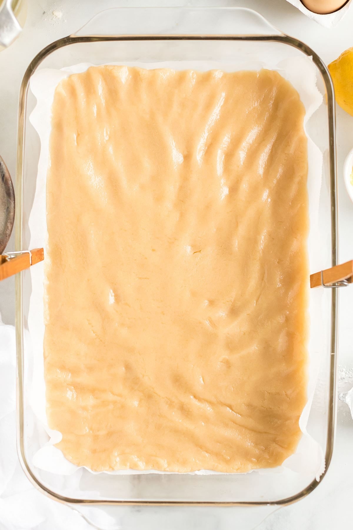 Shortbread crust pressed into a parchment-lined glass baking dish.