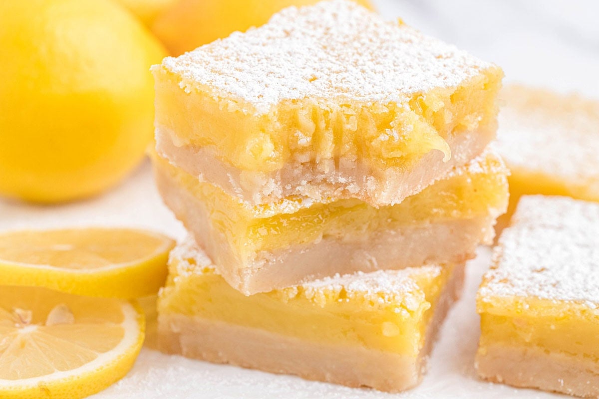 Three stacked lemon bars with shortbread crust and powdered sugar.