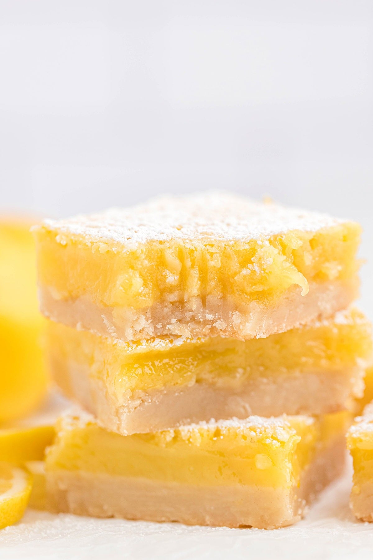 A vertical stack of three lemon bars with a thick crust and powdered sugar dusting.