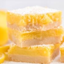 square pieces of lemon bars stacked on top of table.