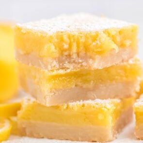 square pieces of lemon bars stacked on top of table.