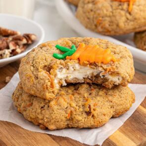 Carrot cake stuffed cookies with a creamy cheesecake filling, topped with a small icing carrot decoration.