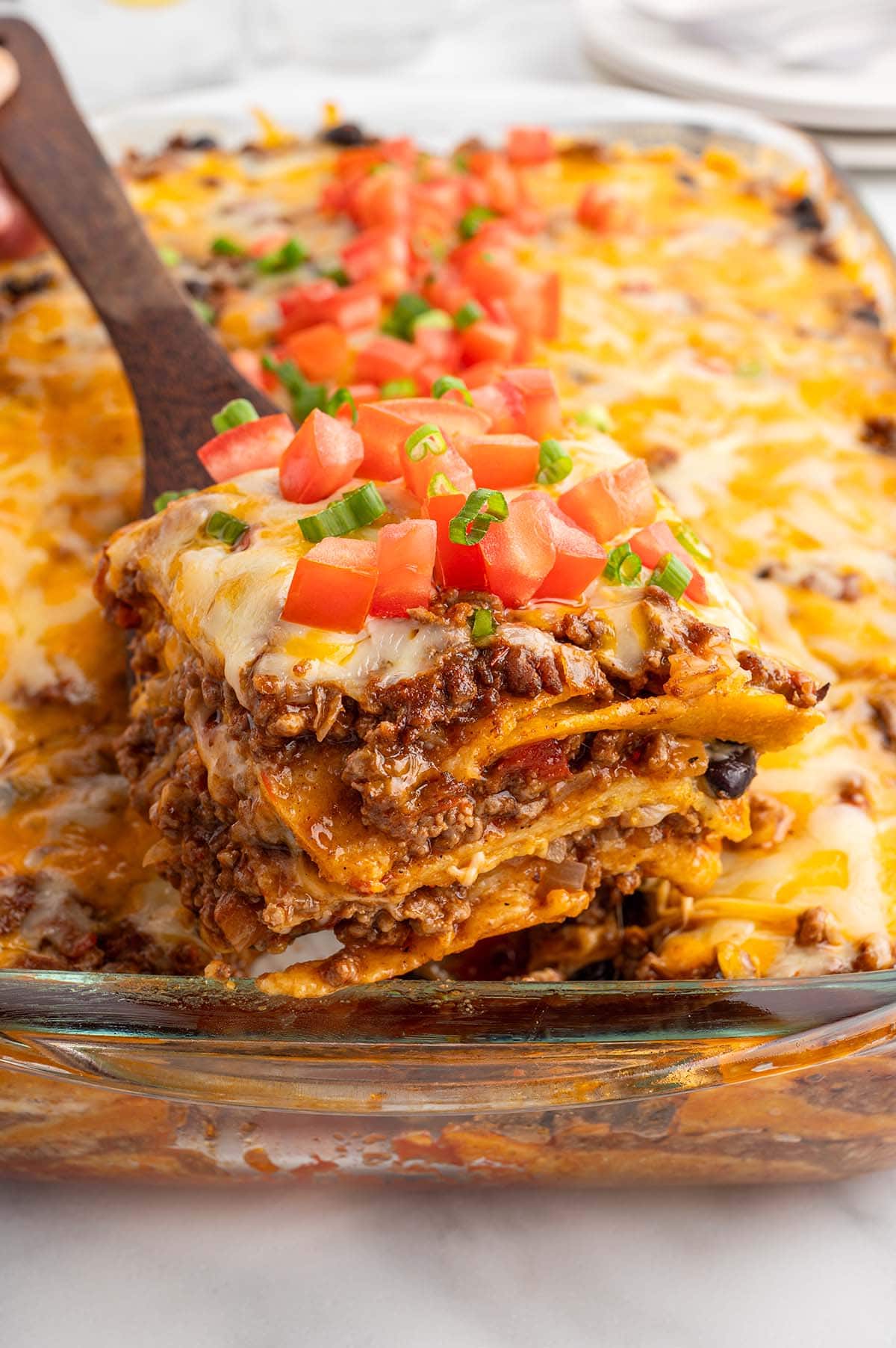 cutting a big square piece of mexican casserole.