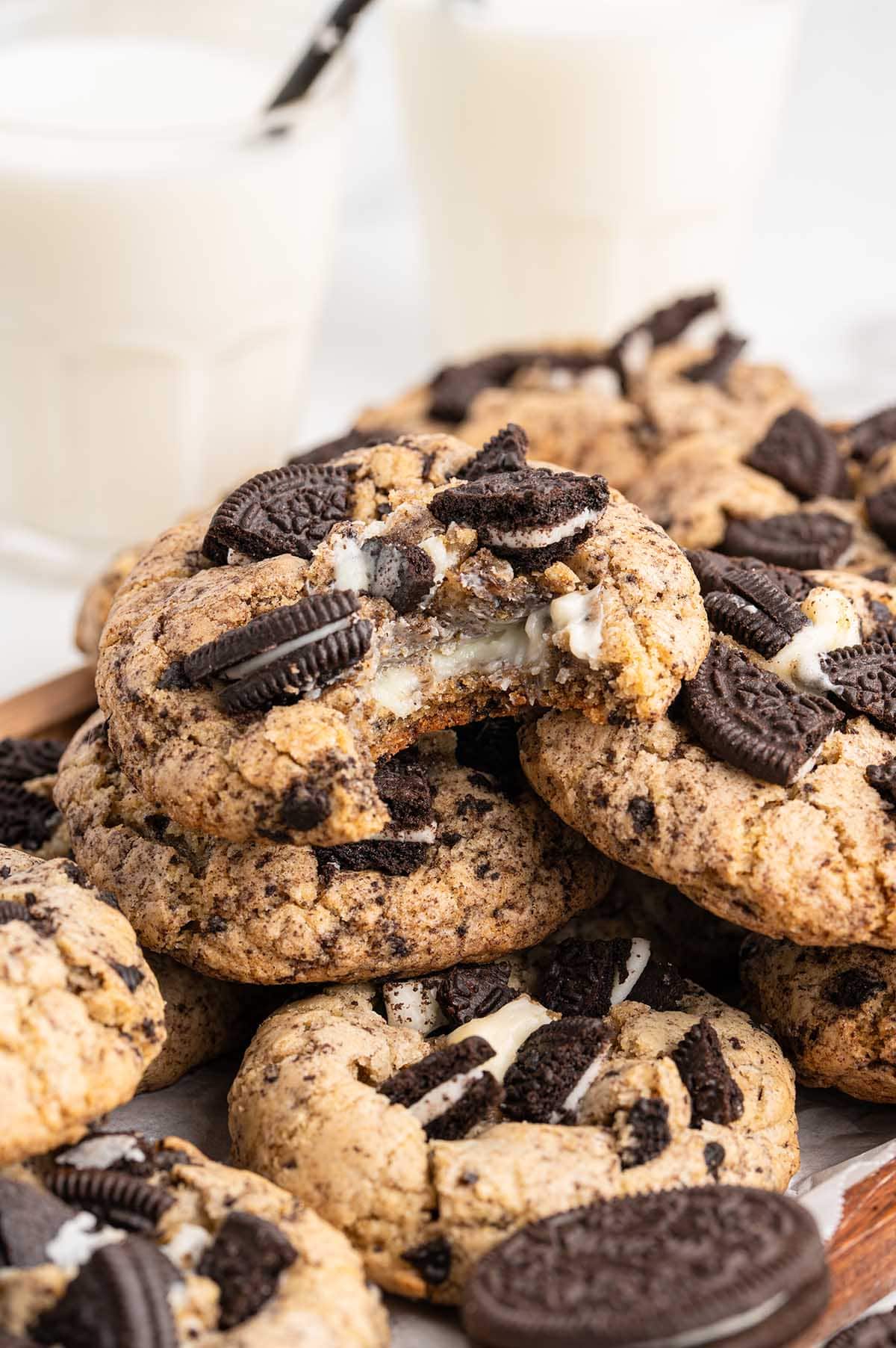A pile of thick Oreo cookies with a creamy white cheesecake center visible in a broken cookie on top.