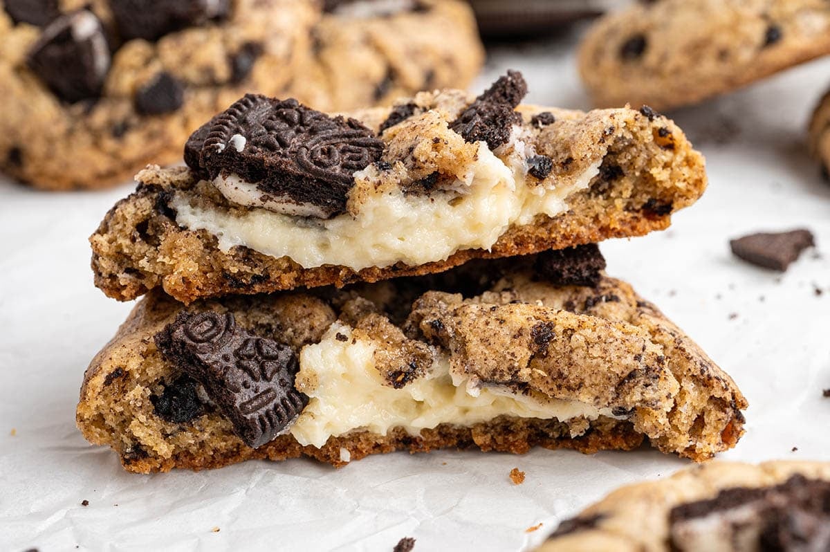 A close-up of a halved Oreo cheesecake cookie showing the soft cream cheese filling and chunks of chocolate cookie.