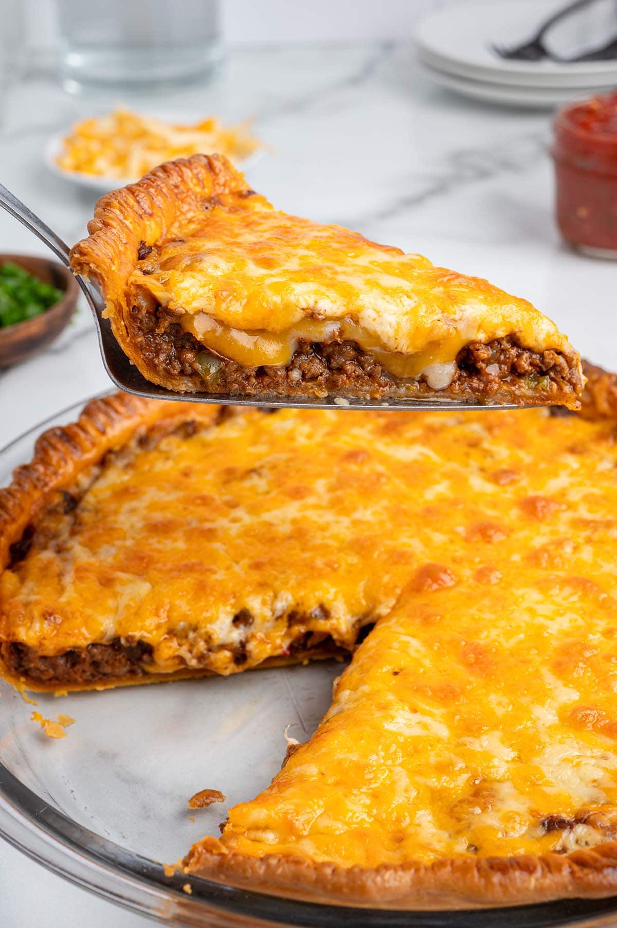 Savory ground beef filling seasoned with peppers and onions spread into a golden pie crust before adding the cheese topping.