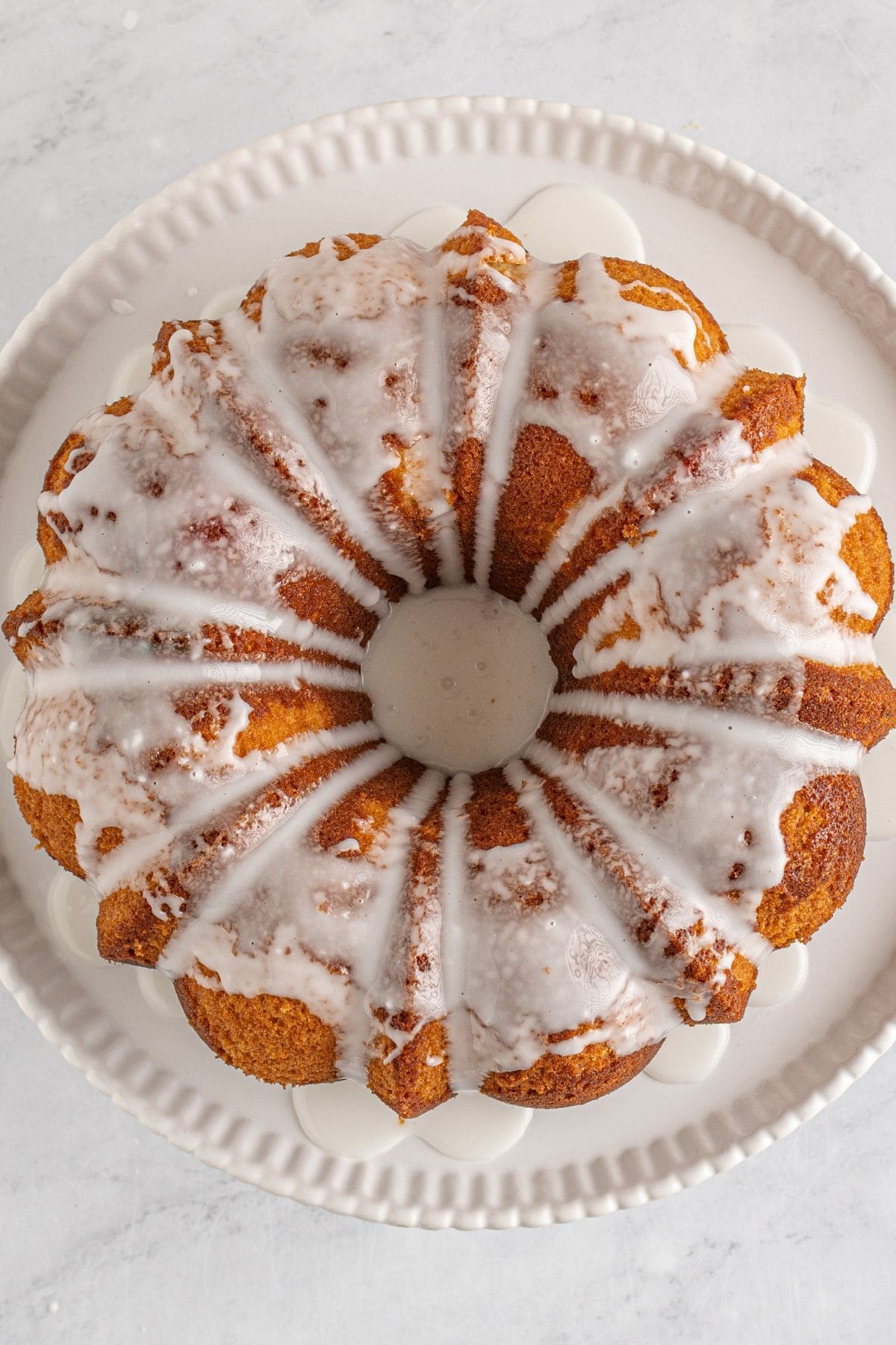 7UP pound cake drizzled with white glaze on a white cake stand.