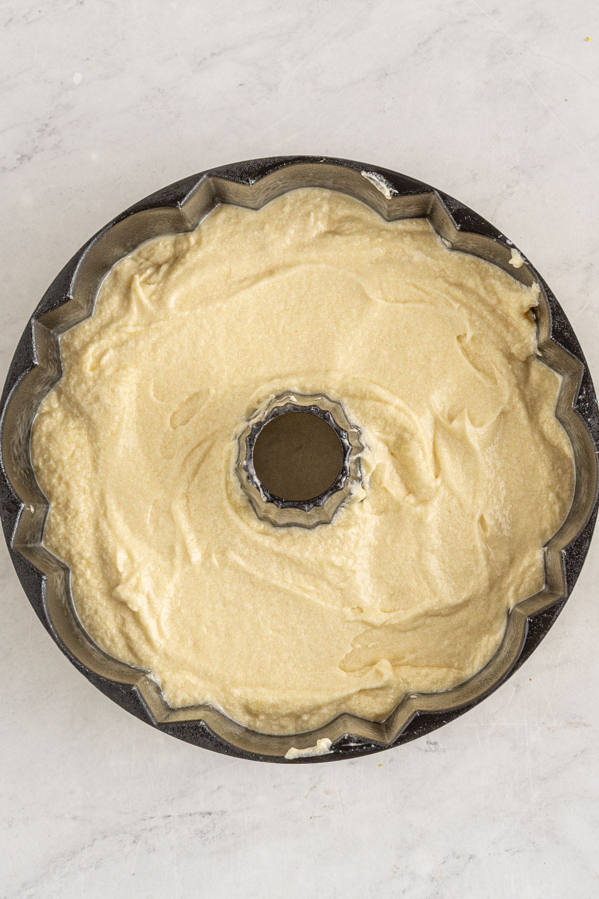Pound cake batter poured into a greased bundt pan ready to bake.