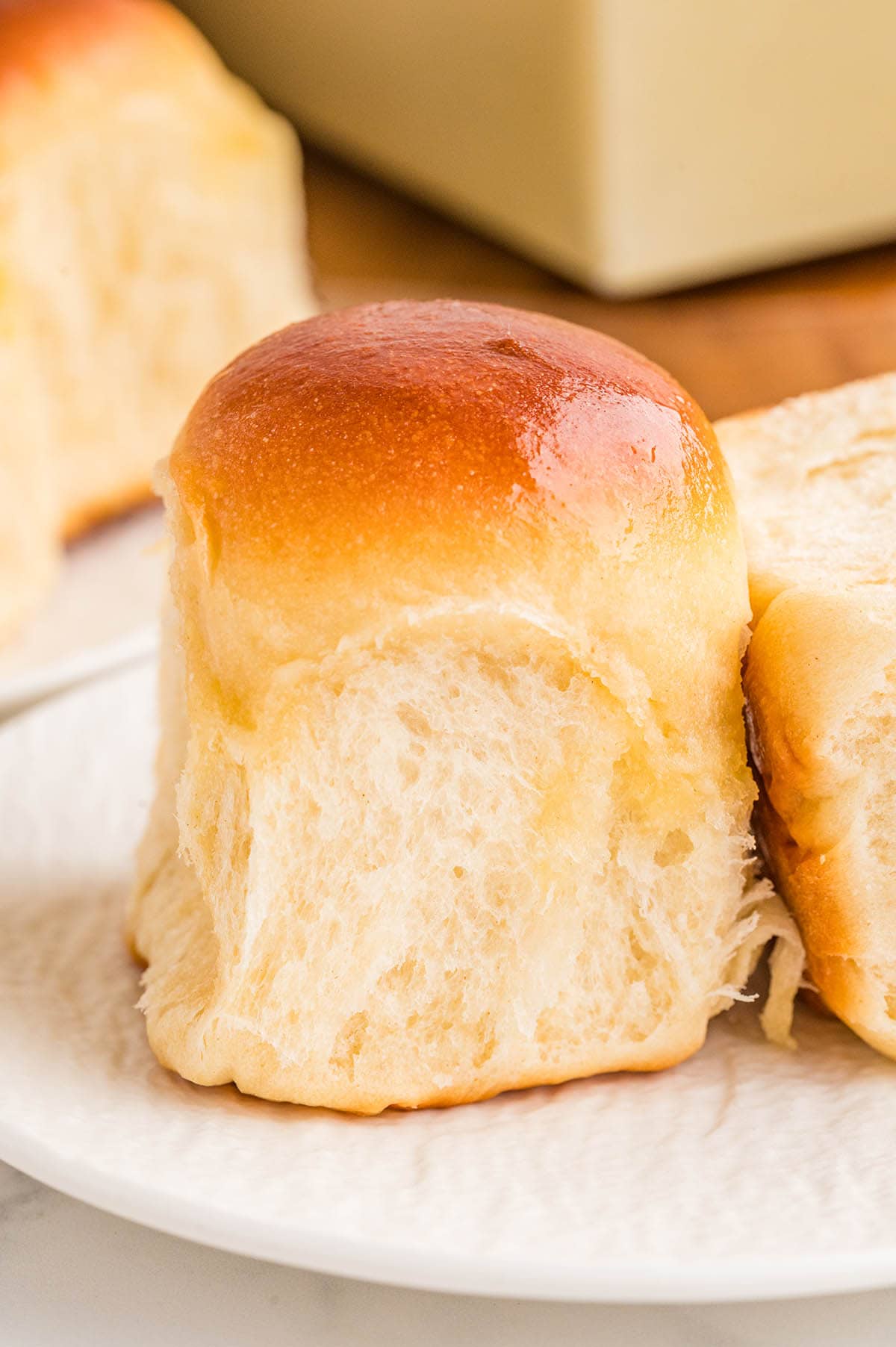 Close-up of a soft cafeteria roll showing a fluffy, pillowy interior with a golden brown buttery crust.