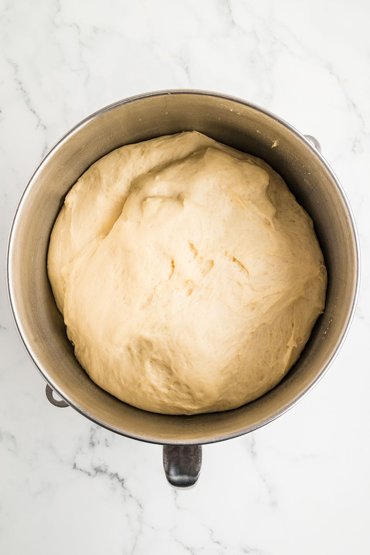 Cafeteria roll dough doubled in size after the first rise in a stand mixer bowl.