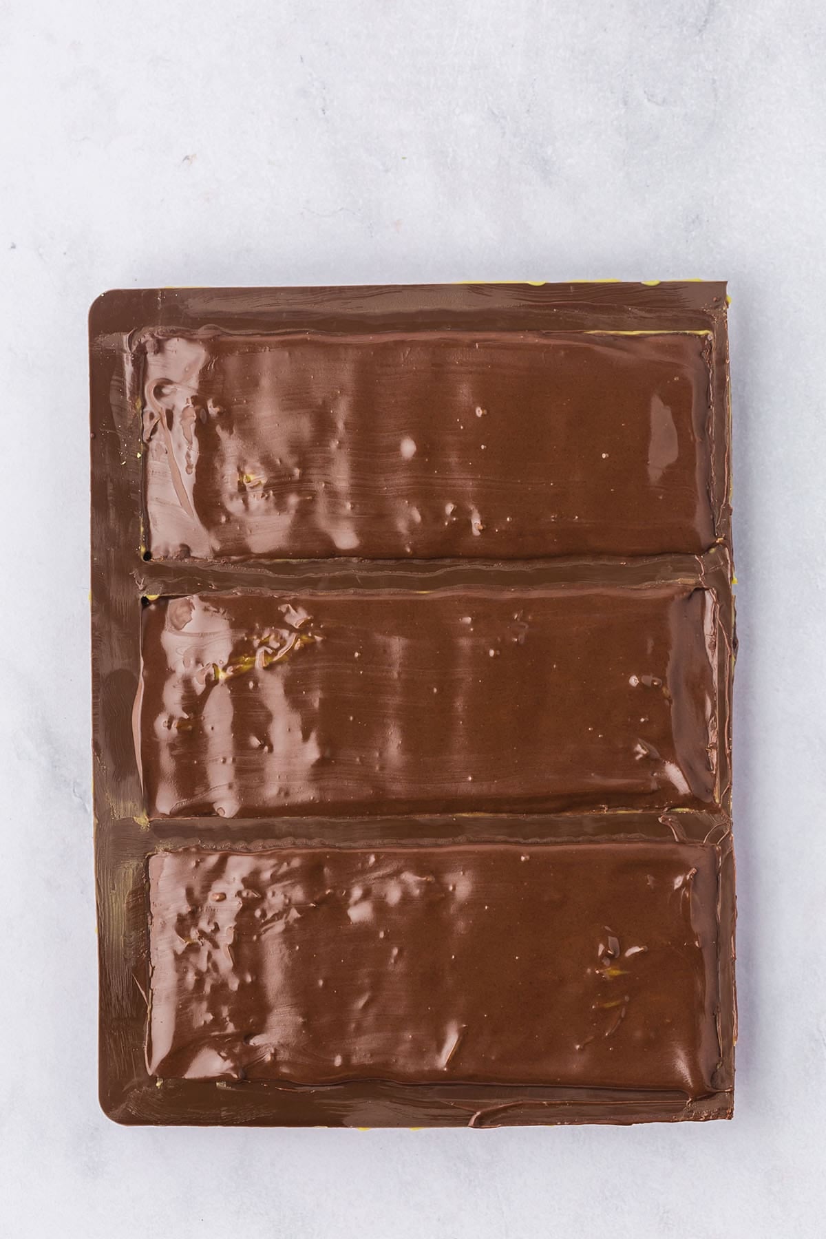 Chocolate bar mold with smooth dark chocolate backs sealing in the pistachio kataifi filling.