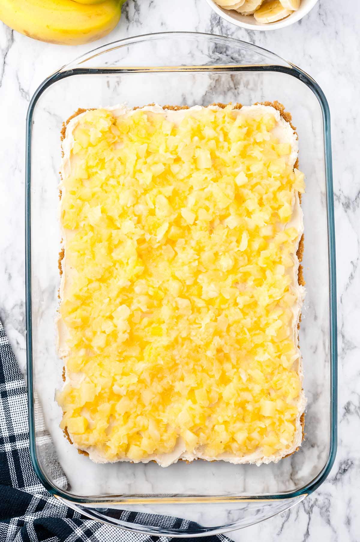 Crushed pineapple layer spread over the cream cheese filling in the glass baking dish.