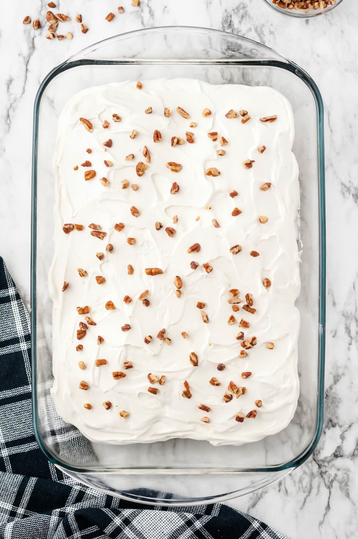 Whipped topping spread over the banana split cake and sprinkled with chopped pecans.