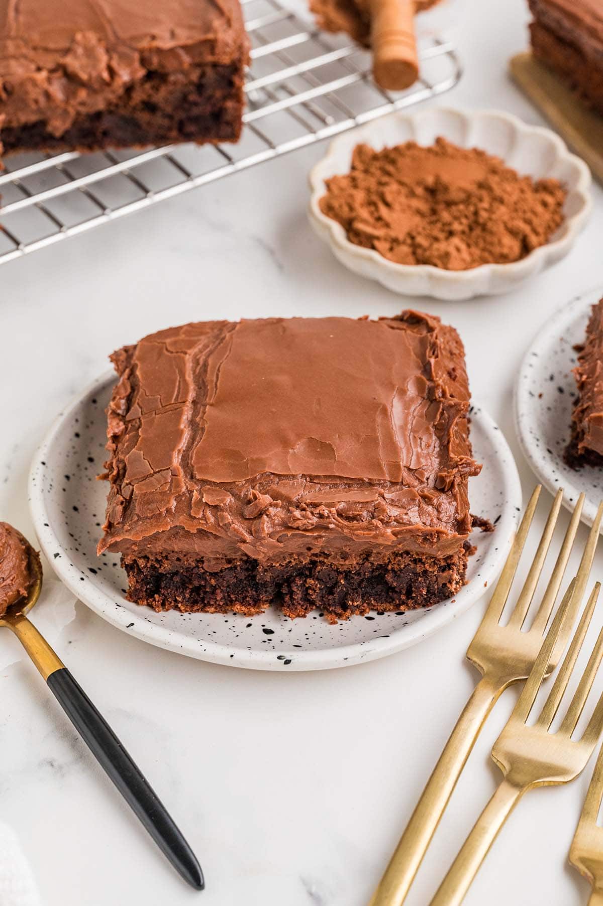 Chocolate brownie with thick frosting on a plate with forks nearby.