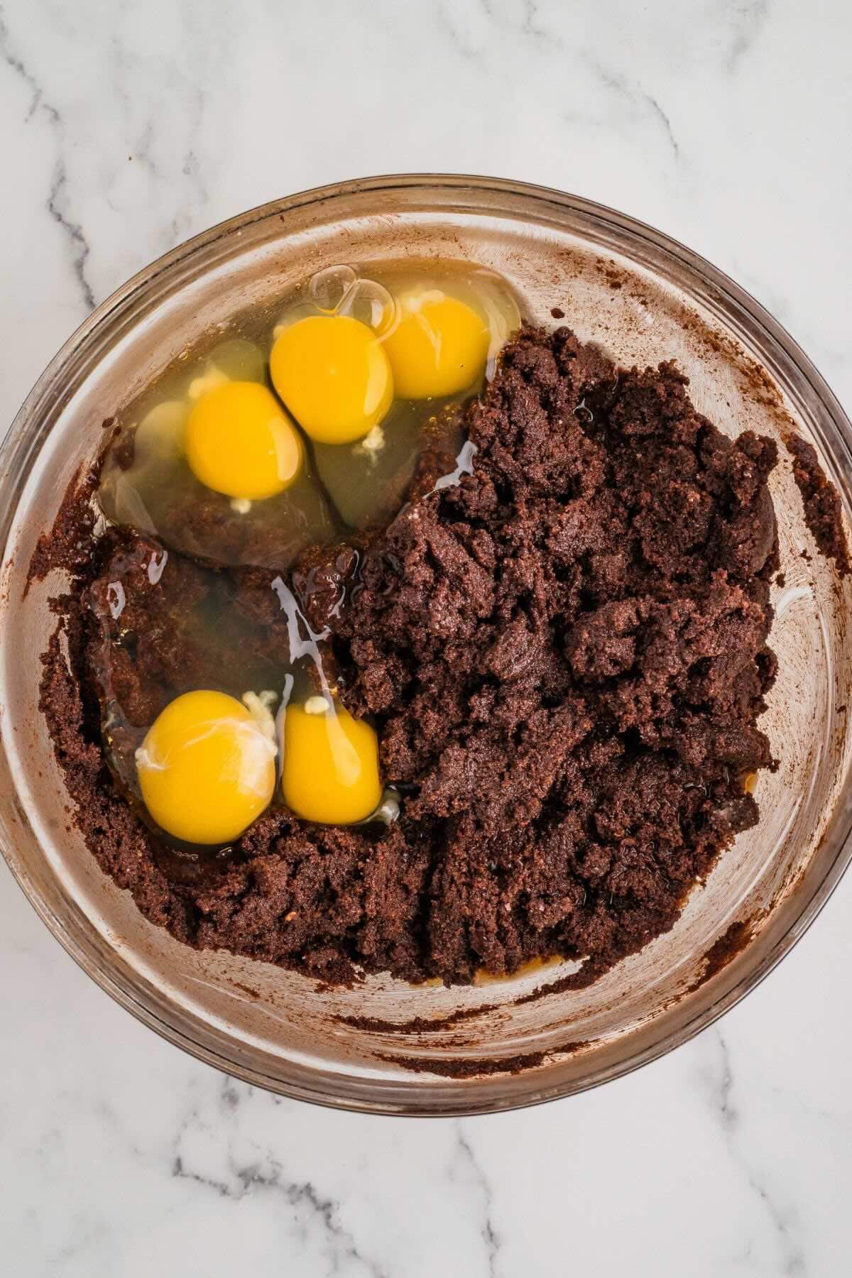 Brownie batter with eggs in a mixing bowl before stirring.
