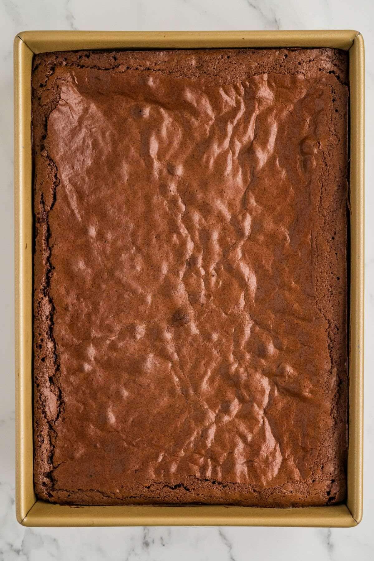 Baked brownies in a rectangular pan with a crackly top.