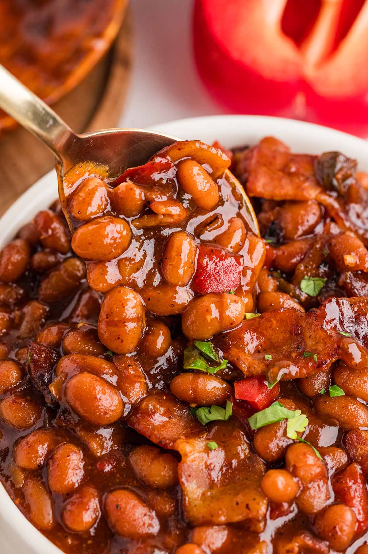 Smoked baked beans in a bowl with golden spoon.