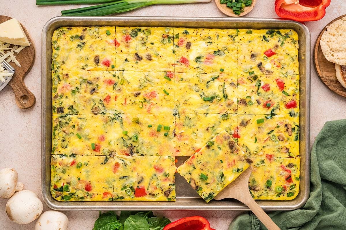 Sheet pan veggie egg bake with peppers, mushrooms, and green onions, sliced and served on a tray.