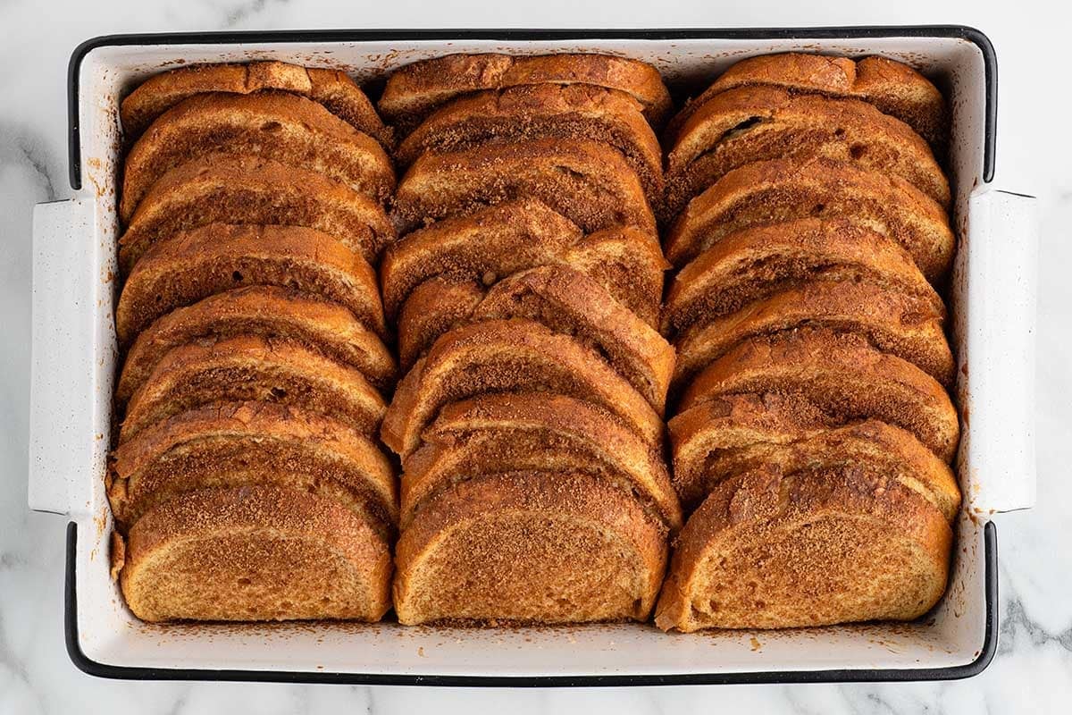 Fully baked French toast with golden cinnamon sugar crust in a white baking dish.