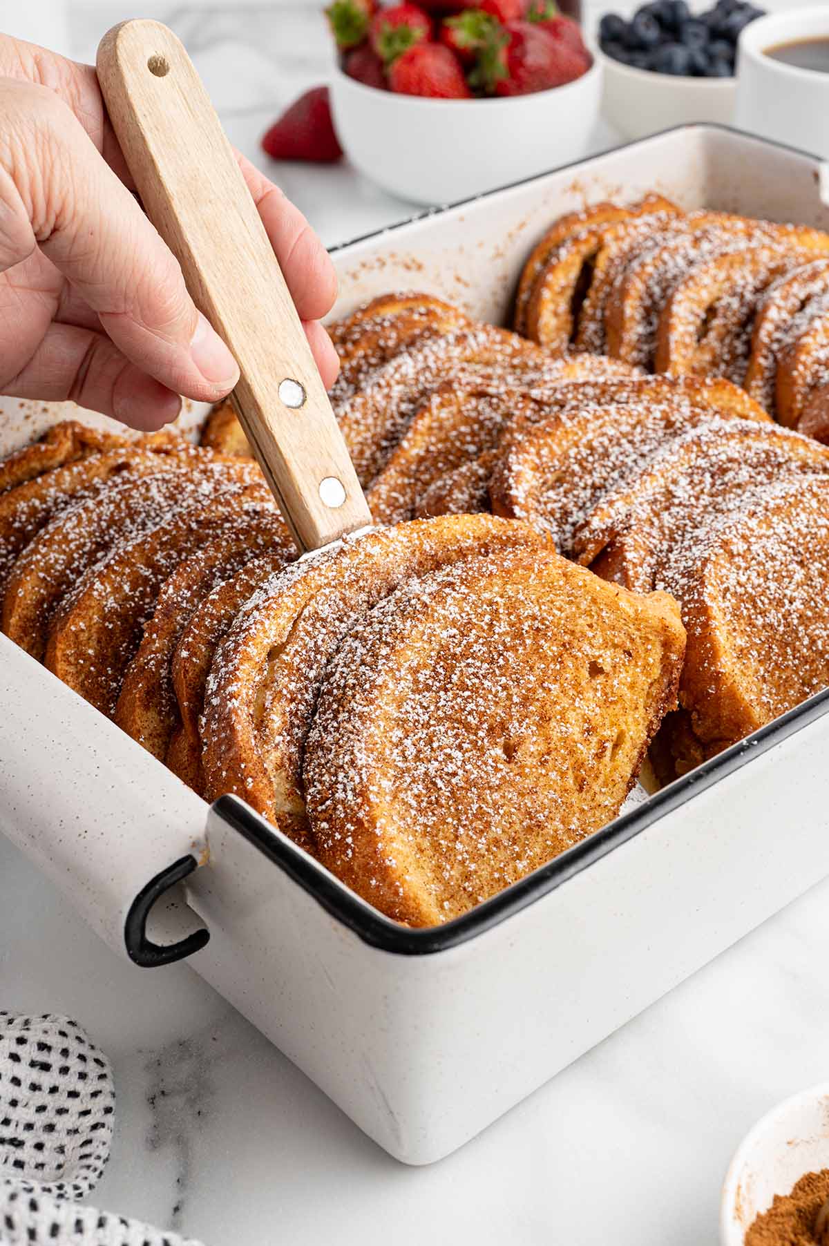 talking a couple of french toast from the casserole dish using spatula. 