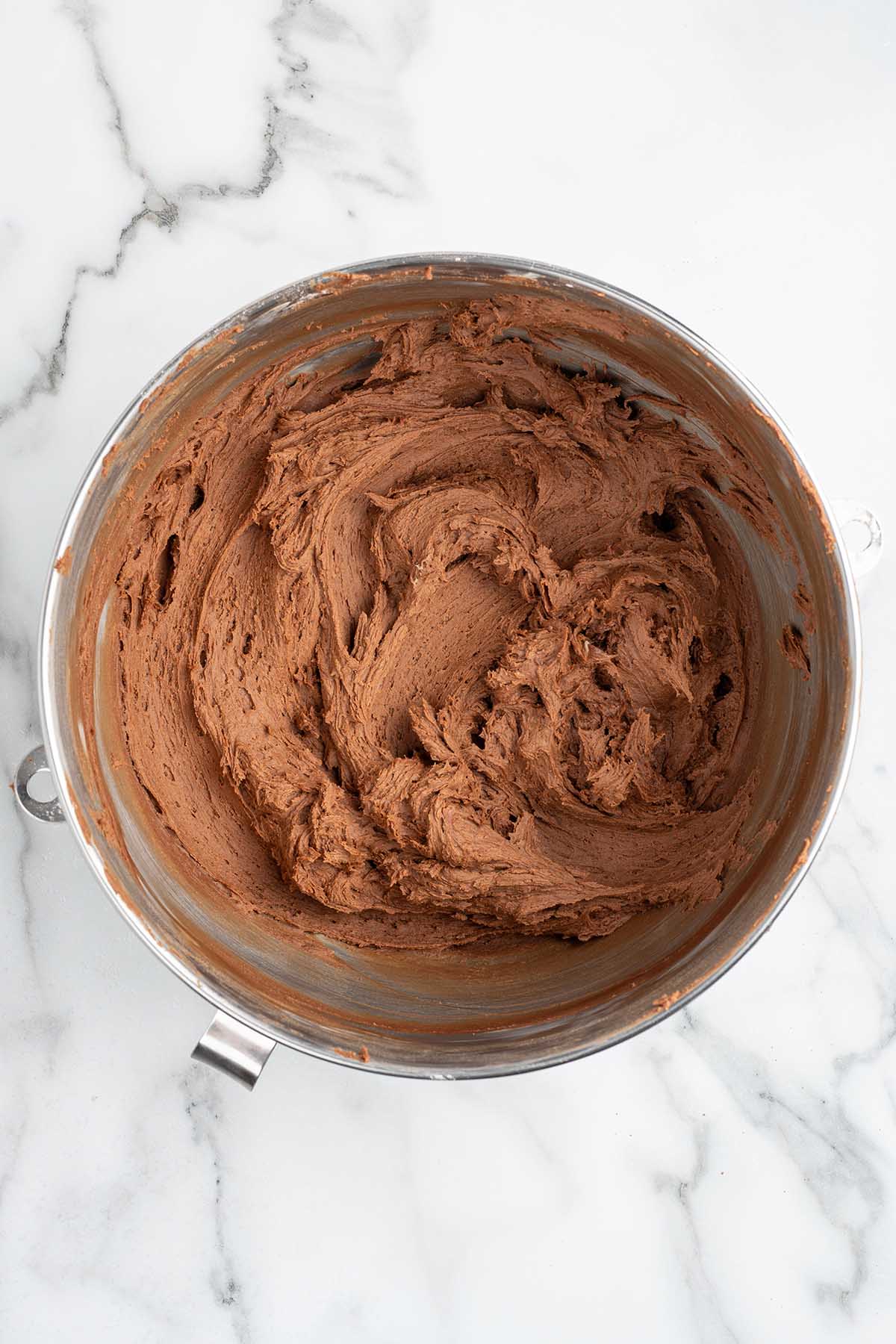 Fluffy chocolate buttercream frosting in a stainless steel stand mixer bowl.