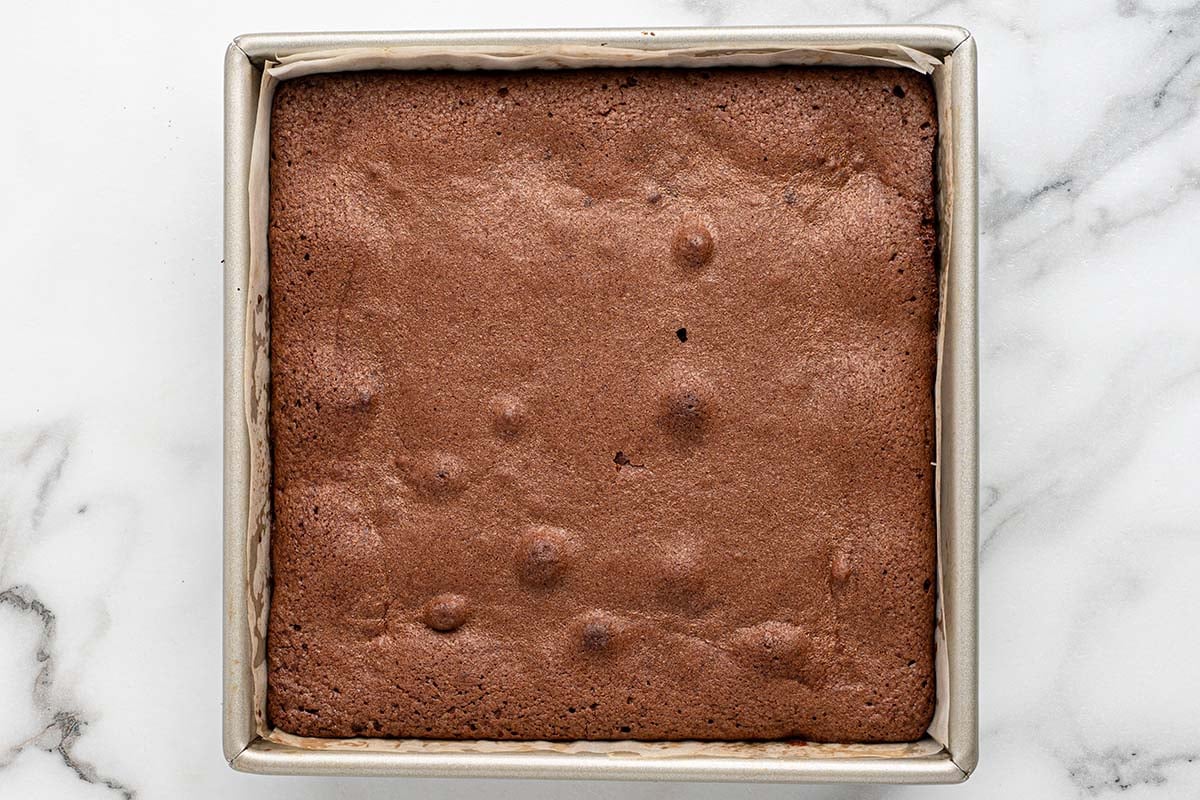 Fresh chocolate brownies with peanut butter cups in a parchment-lined pan.