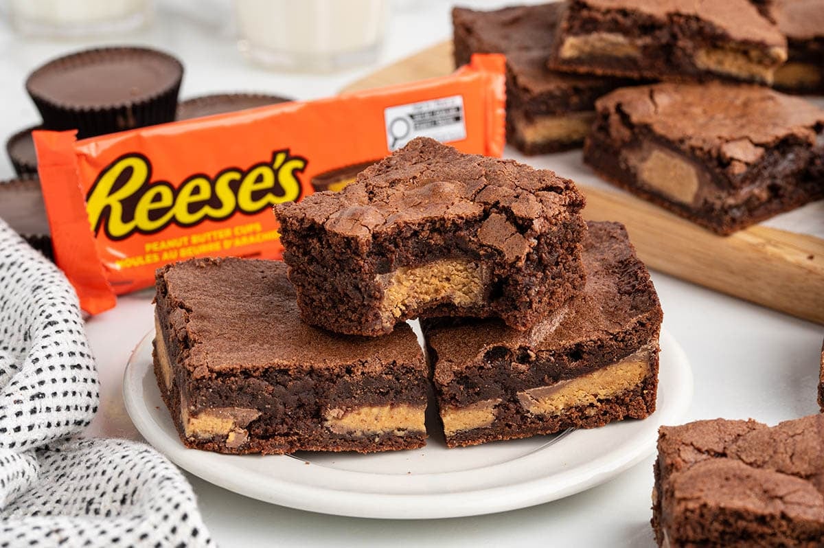 Fudgy brownies filled with peanut butter cups on a plate.