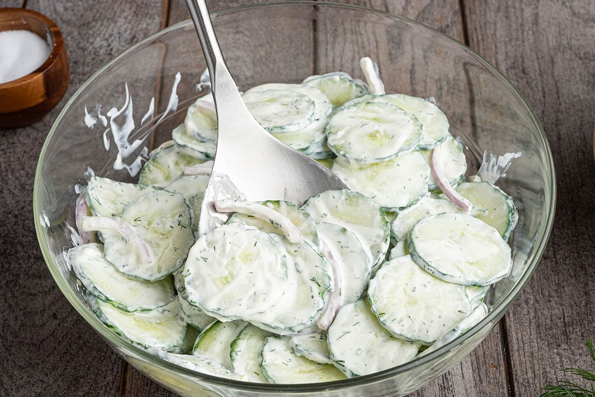 Creamy cucumber salad with sliced cucumbers and onions in a bowl.