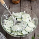Creamy cucumber salad with sliced cucumbers and onions in a glass bowl.