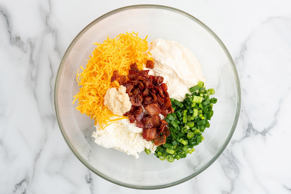 Million dollar dip ingredients unmixed in a glass bowl.
