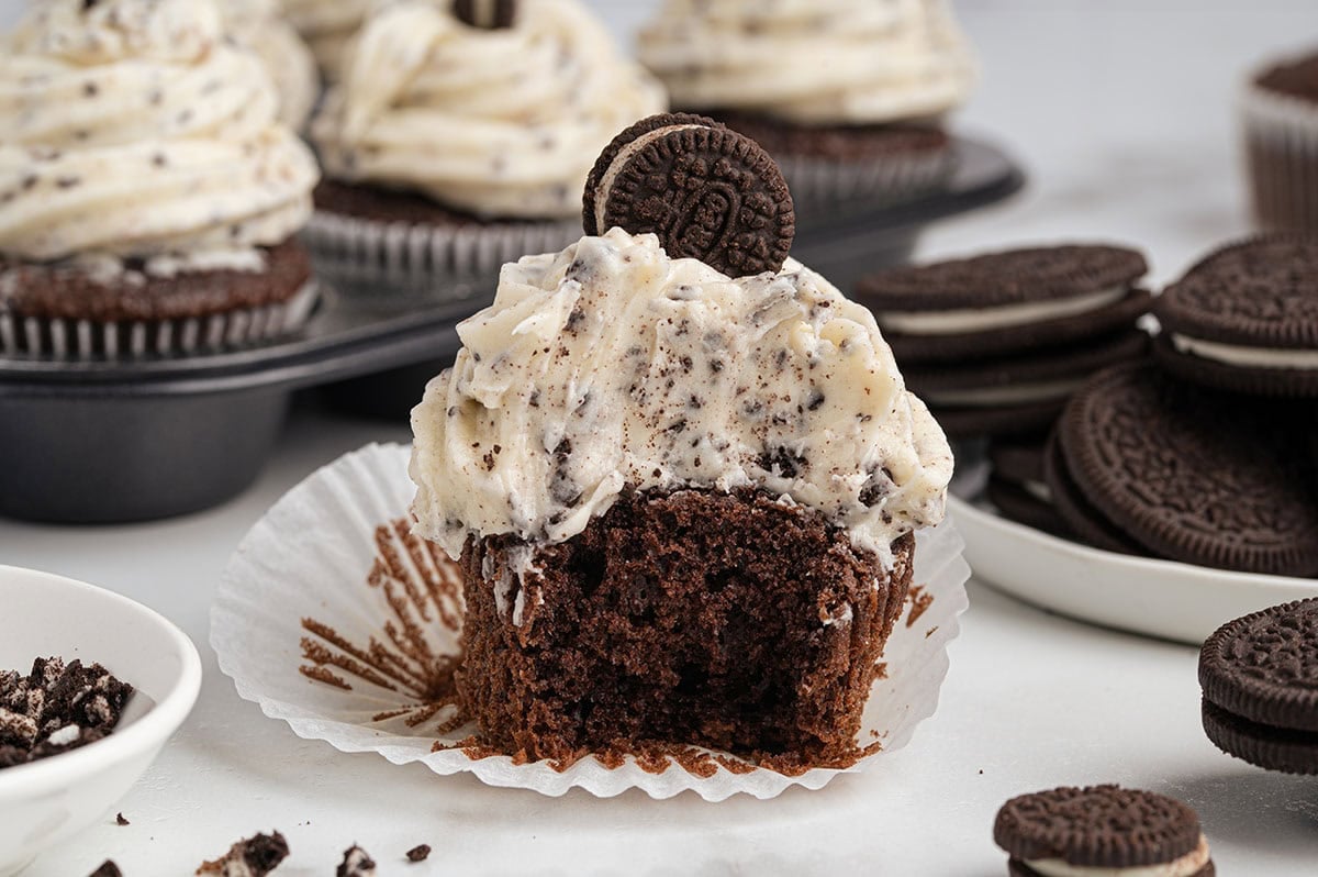 Chocolate cupcake with cookies and cream frosting and a bite taken out, topped with a mini Oreo.