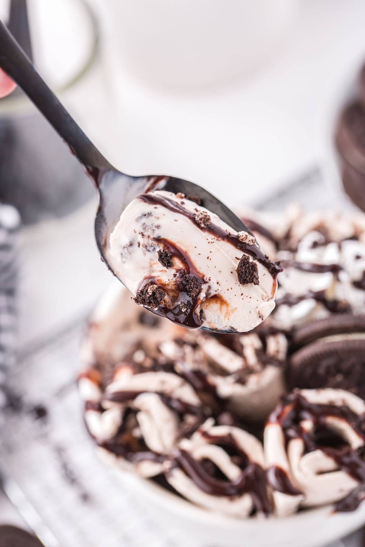 Spoonful of Oreo ice cream drizzled with chocolate sauce.