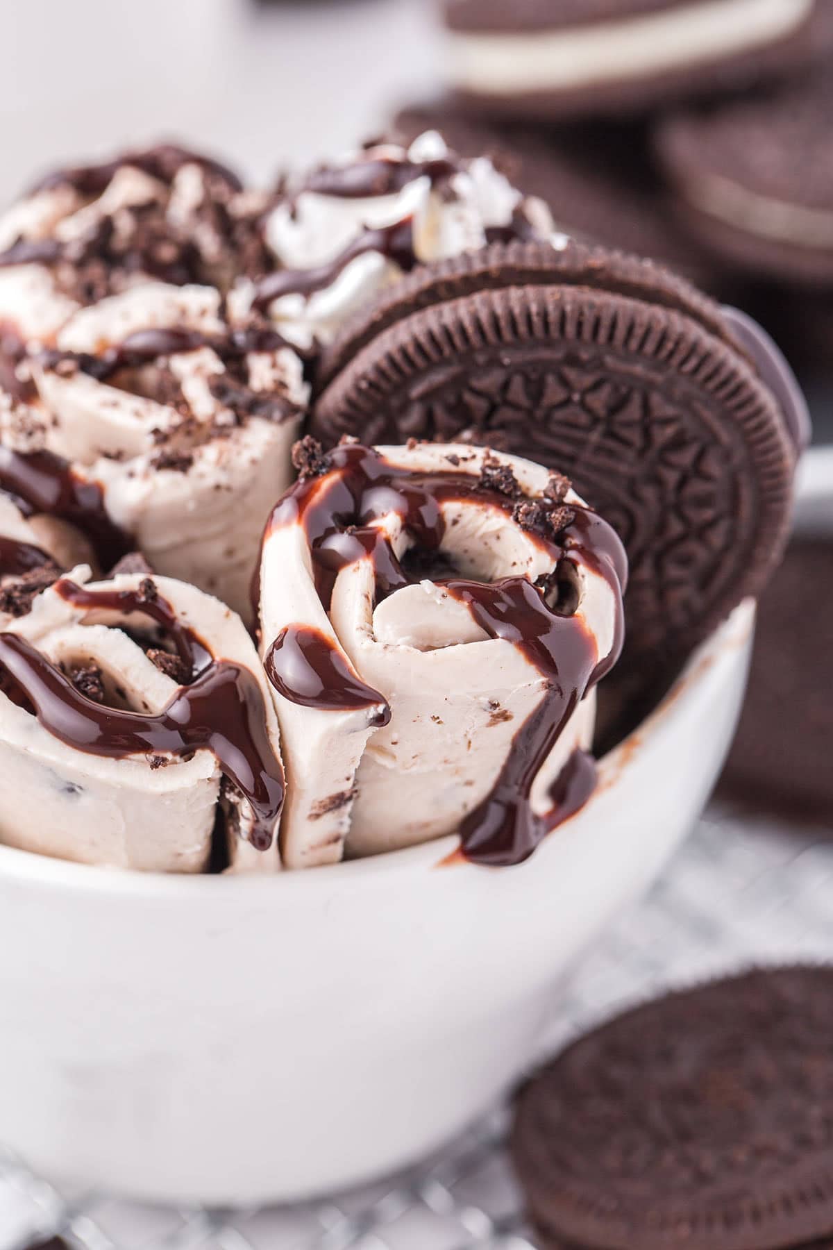 Close-up of creamy Oreo rolled ice cream drizzled with chocolate sauce and topped with cookie crumbs.