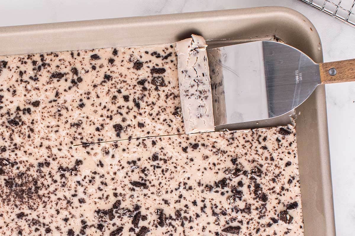 Oreo ice cream rolled up with a spatula on a frozen pan.