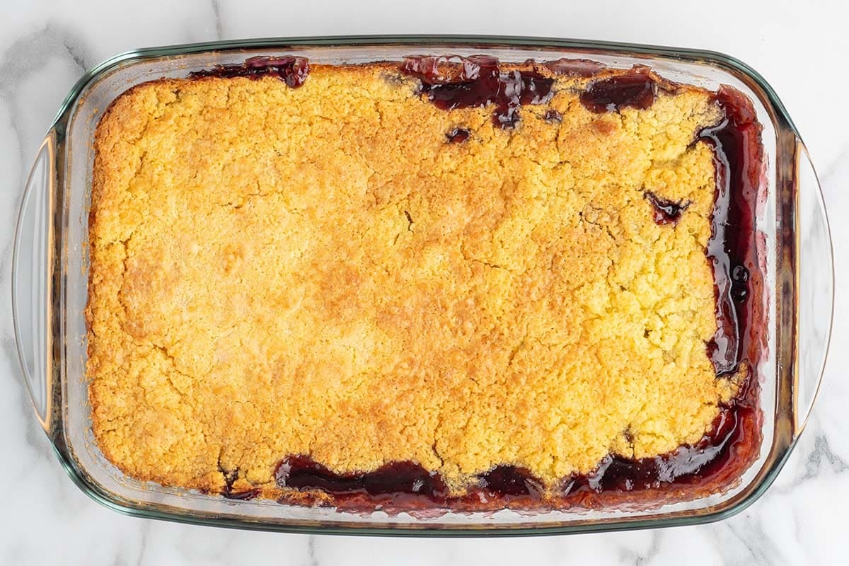 Freshly baked blueberry dump cake with golden cake topping and bubbling blueberry filling in a glass baking dish.