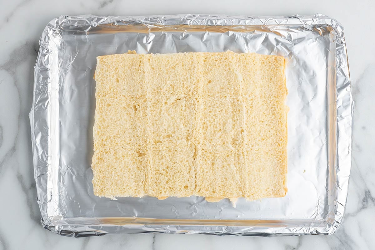 Overhead view of slider buns placed on a foil-lined baking sheet, prepared as the base for buffalo chicken sliders.