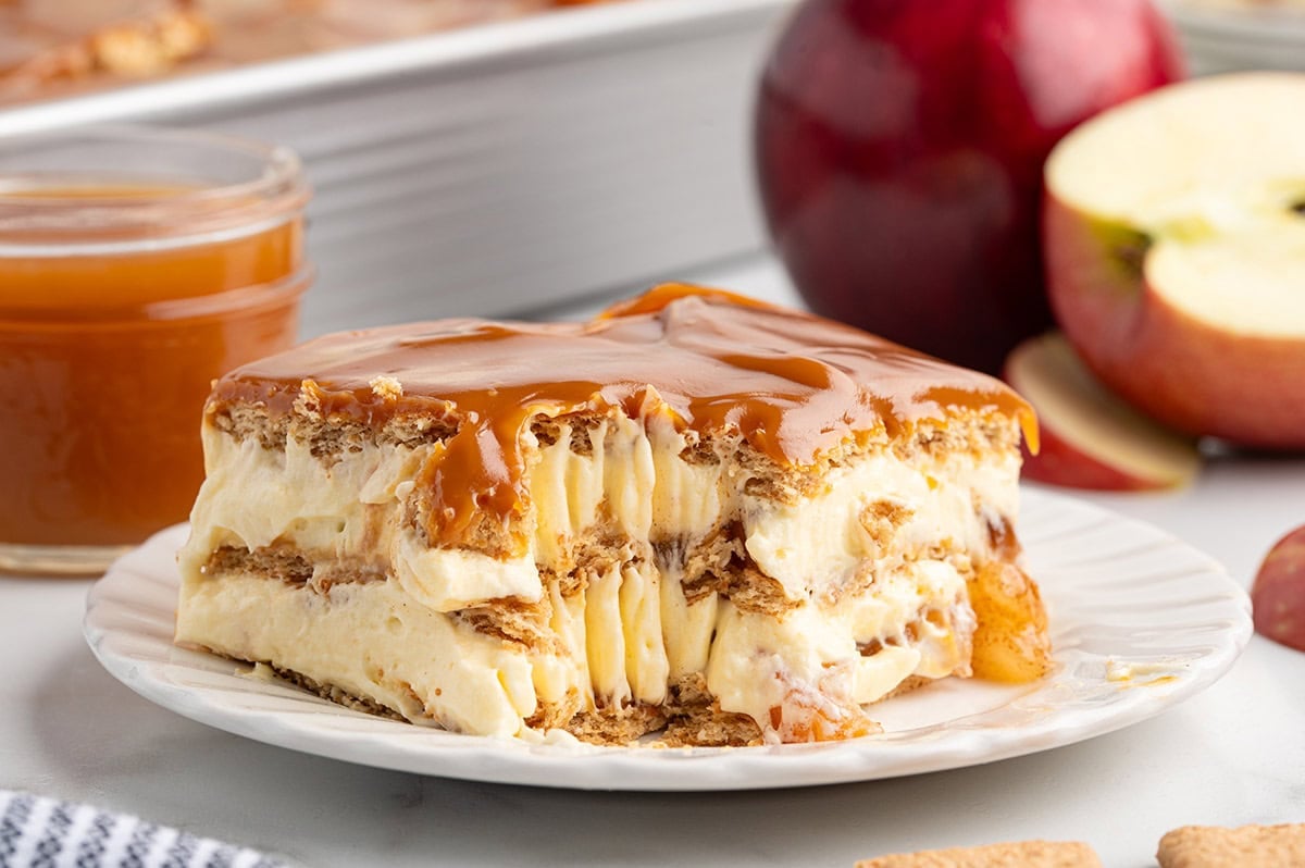 Slice of caramel apple eclair cake with creamy layers, tender apples, graham crackers, and a rich caramel topping.