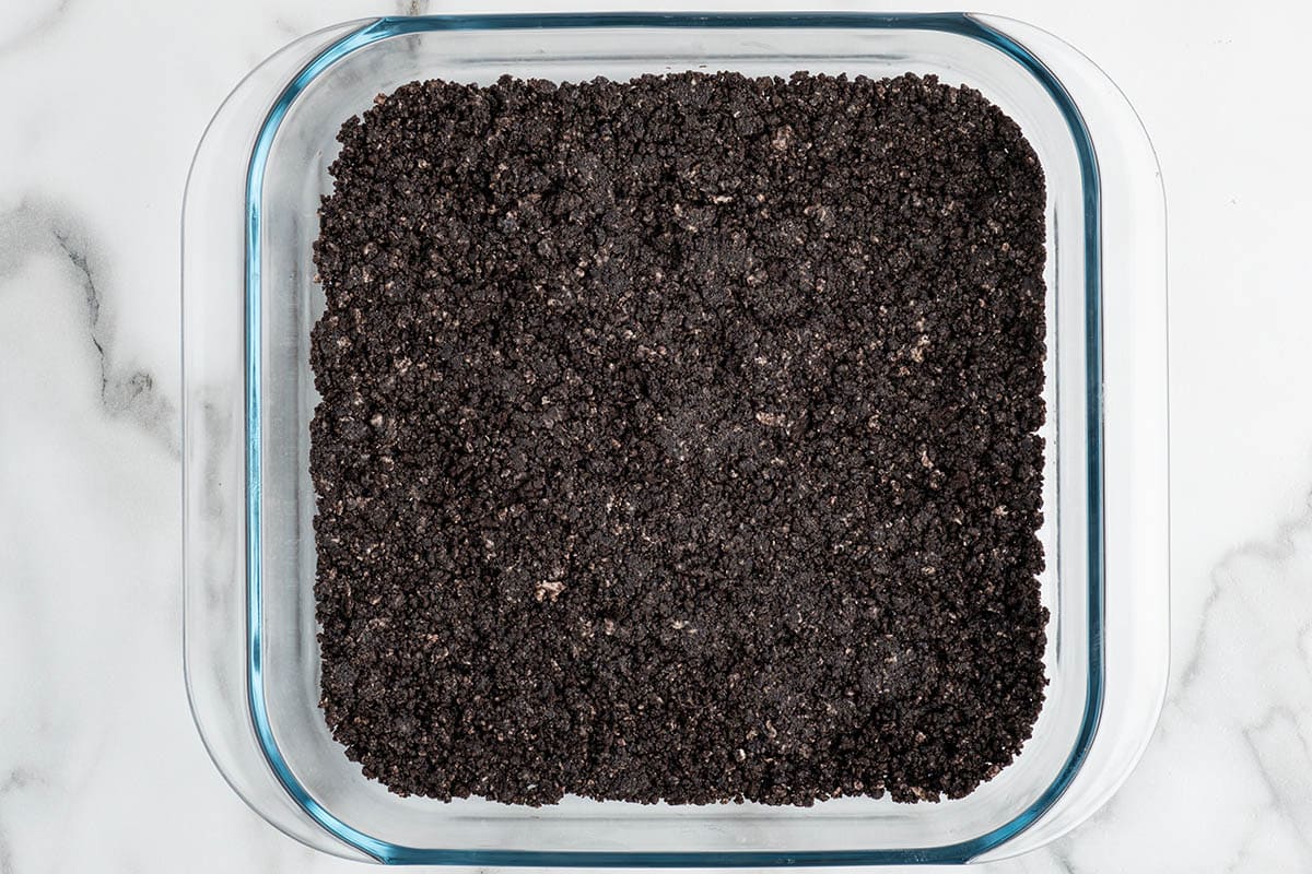 Oreo cookie crust pressed into a baking dish.