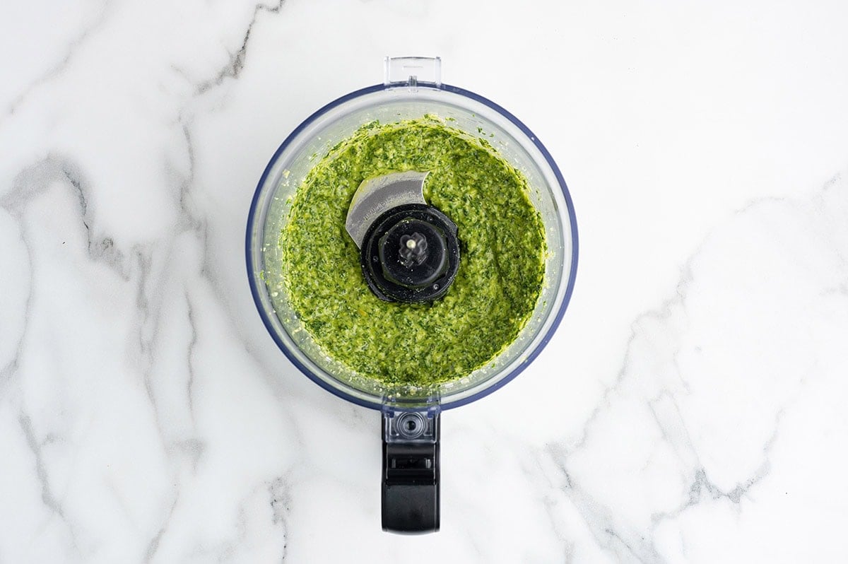 Homemade pesto blended until smooth in a food processor for fresh pasta salad dressing.