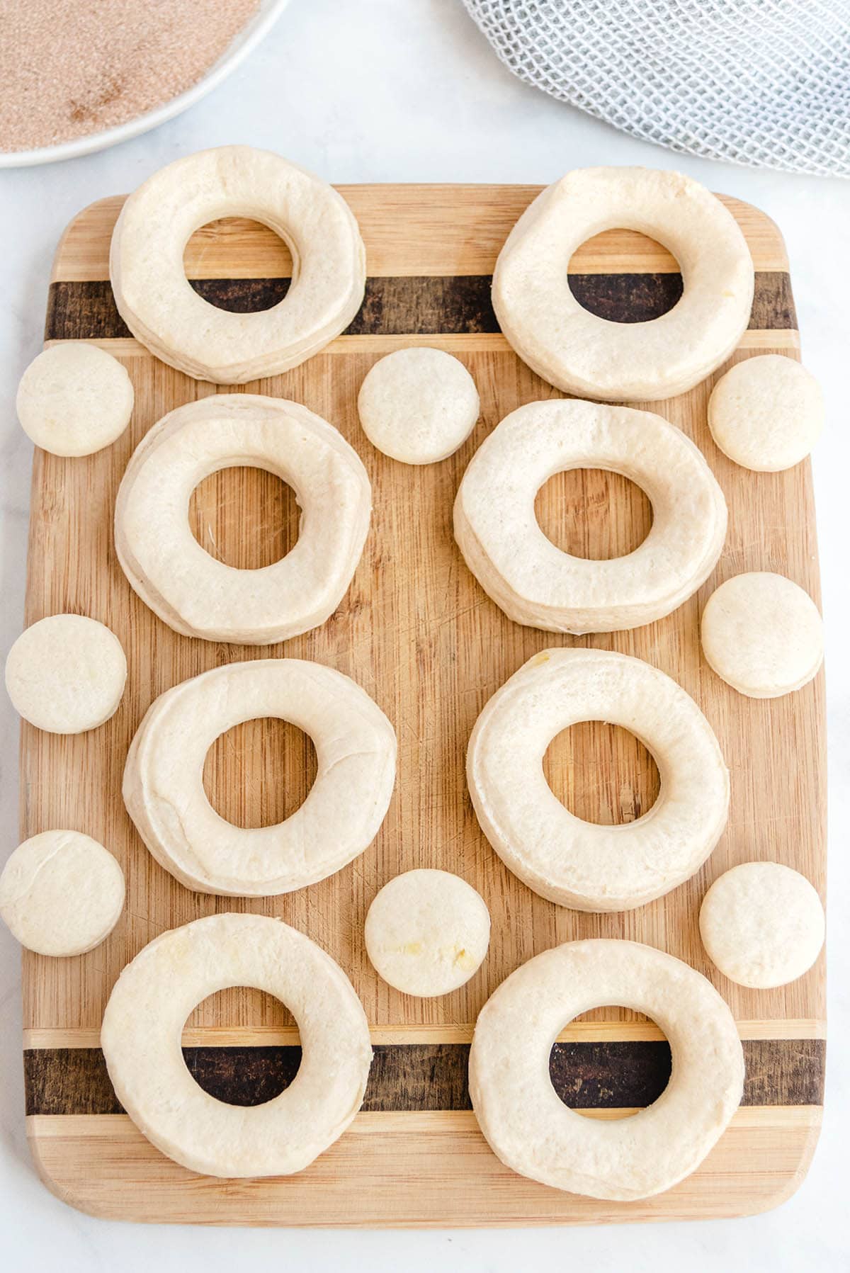pilsbury biscuits with holes cut out on top of wooden board.