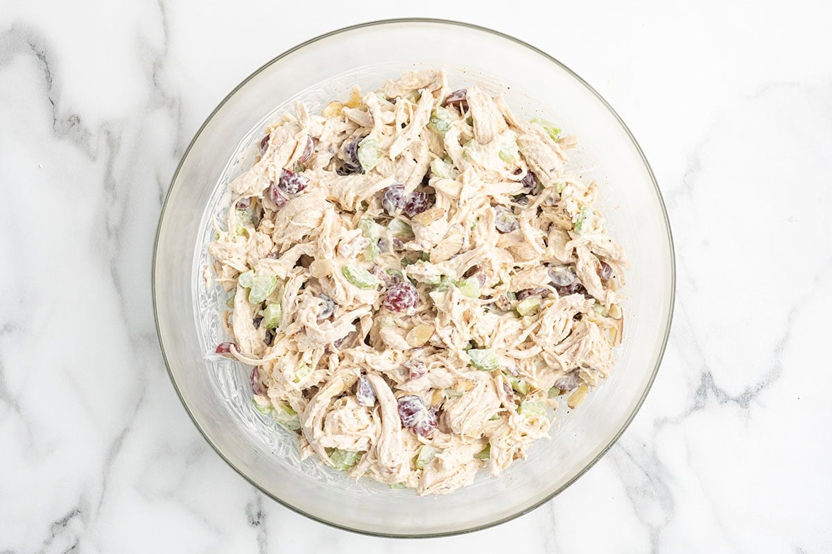 Creamy chicken salad with grapes and celery mixed together in a glass bowl.