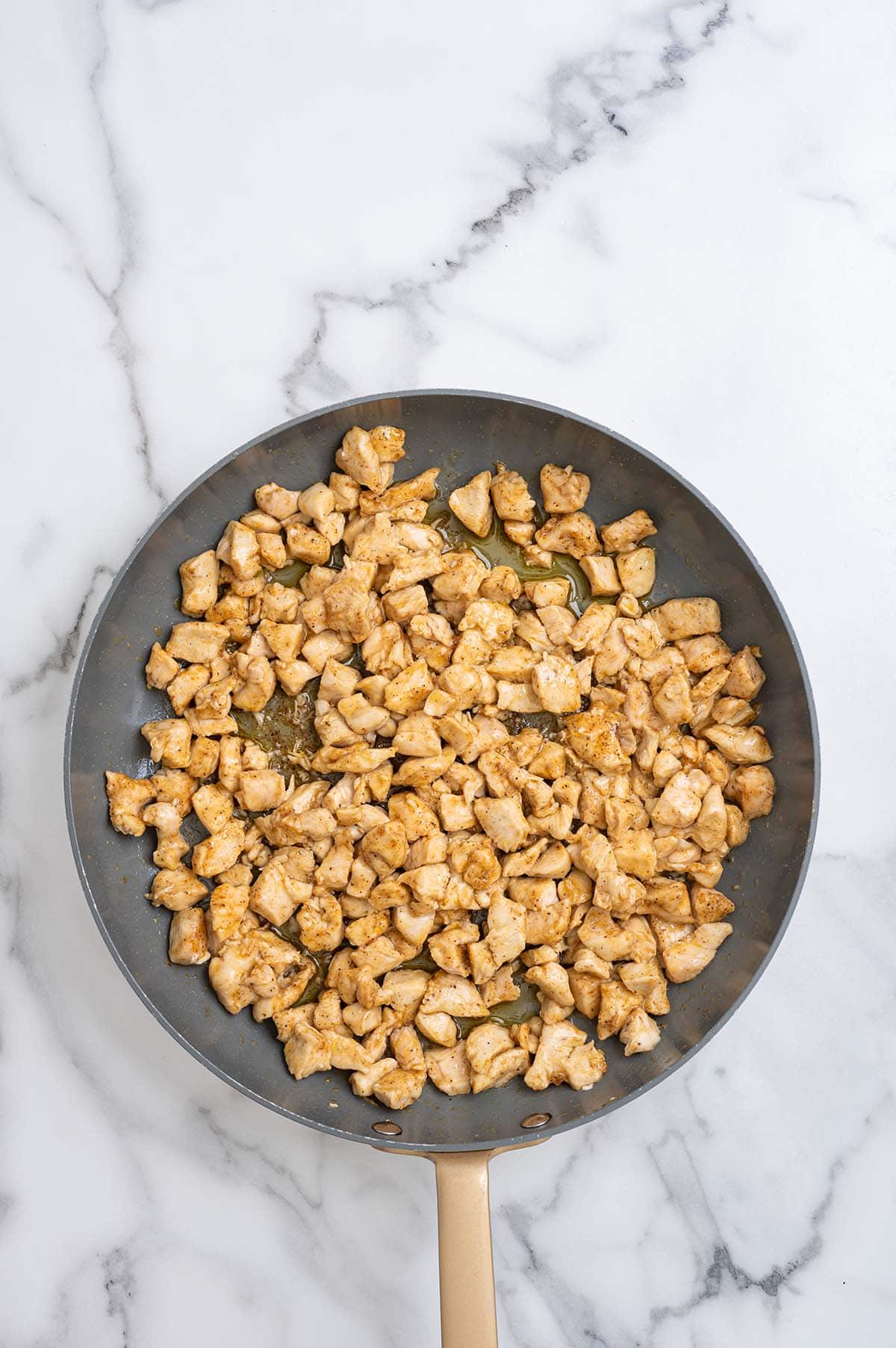 Diced seasoned chicken cooking in a skillet for fajita quesadillas.