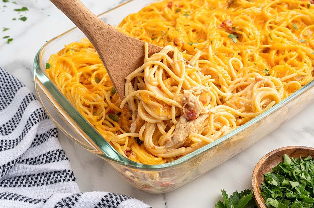 rotel chicken spaghetti being scooped up with wooden spoon.