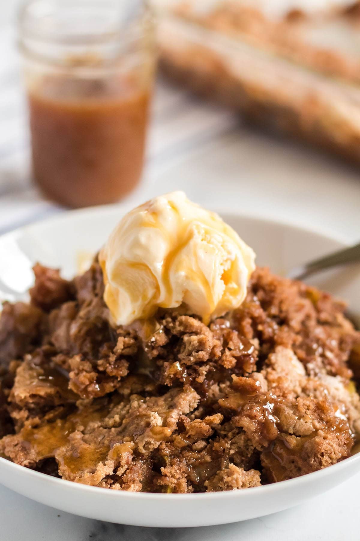 Warm apple dump cake topped with vanilla ice cream and caramel sauce.