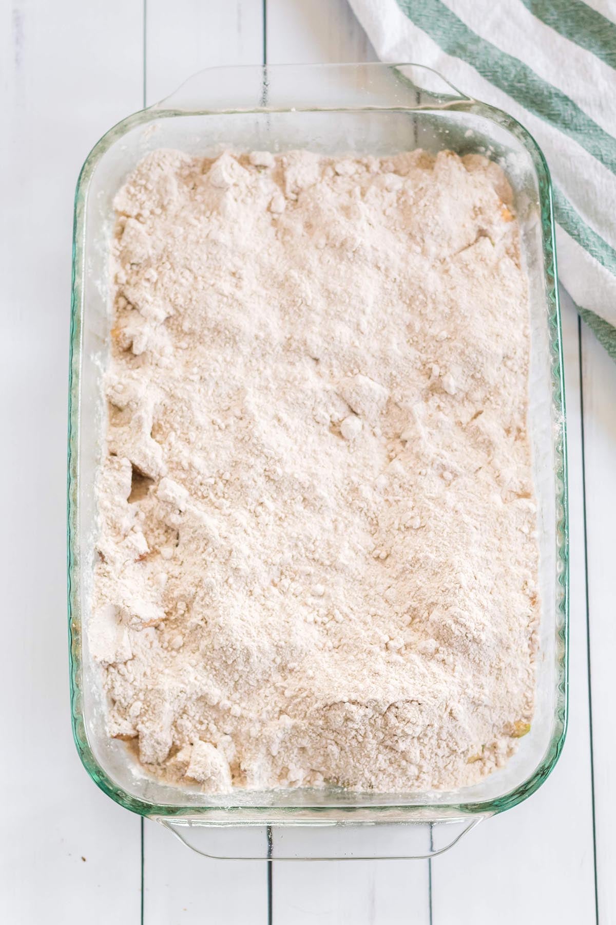 Glass baking dish filled with apple pie filling topped with dry yellow cake mix.